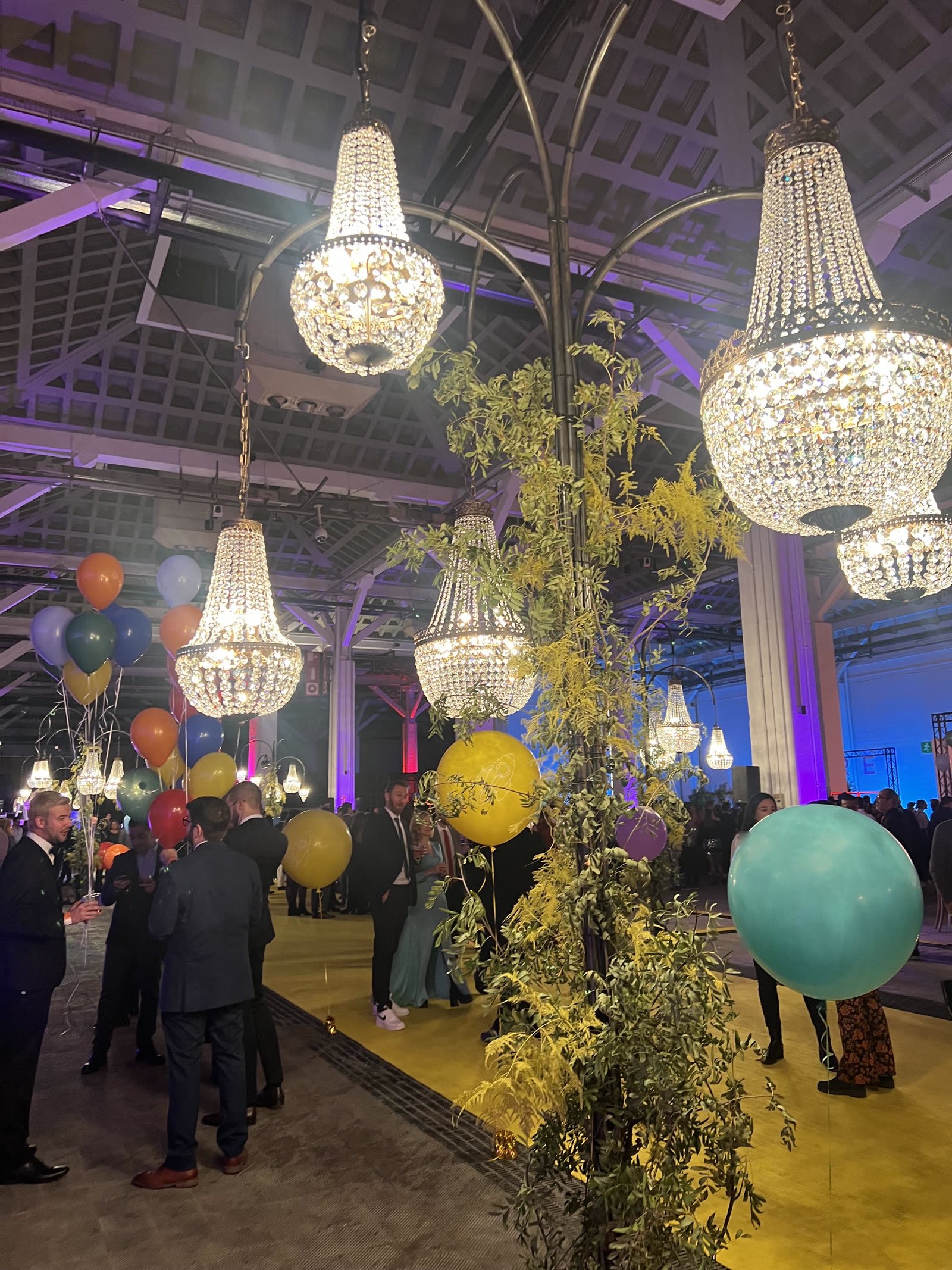Large-scale event with chandeliers and greenery